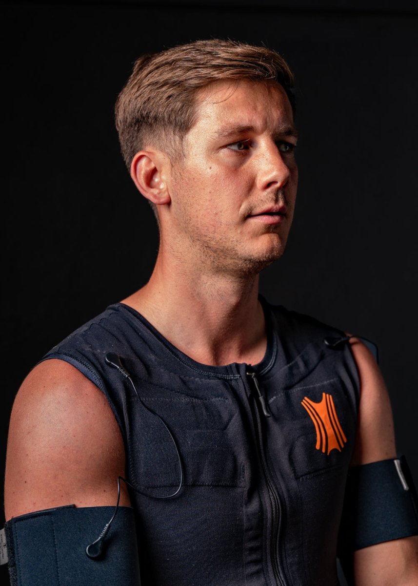 Ein Mann sitzt während des Trainings und trägt den Kraftwunder EMA-Anzug, ein System zur Elektromyoaktivierung zur gezielten Muskelstimulation und Trainingsunterstützung.