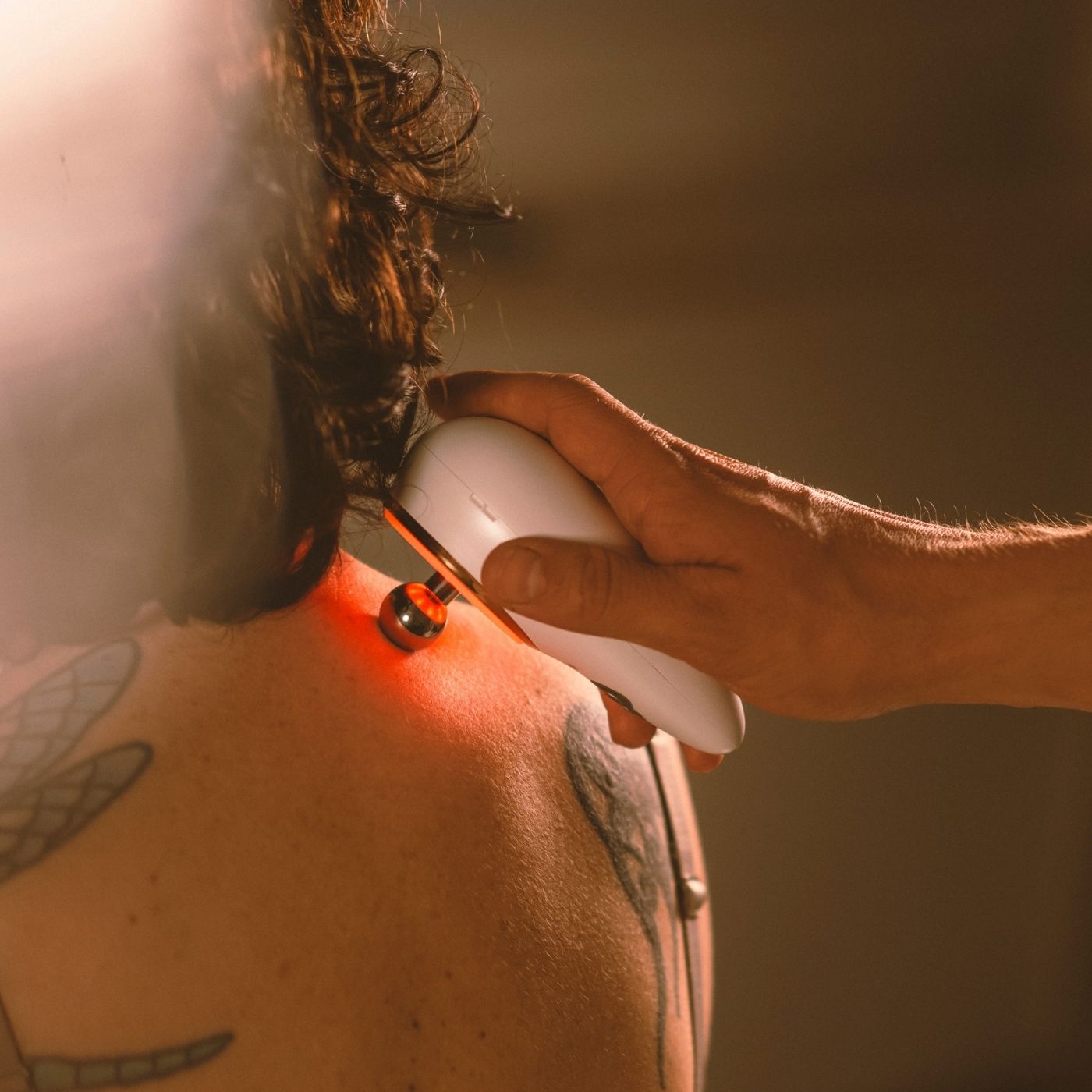 Eine Frau erhält eine Schallwellenmassage im Schulter-Nacken-Bereich zur Linderung von Verspannungen und Förderung der Durchblutung.